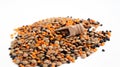 Mixed lentils of different varieties brown, orange and black lie on a white table and next to it is a wooden ladle, spoon, stingy