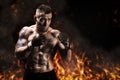 Mixed martial artist posing against the backdrop of fire and smoke. Concept of mma, ufc, thai boxing, classic boxing