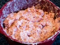 Mixed meatball ingredients, ground meat, onion, breadcrumbs, milk, egg and spices in a red bowl, ready to be rolled