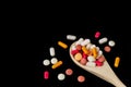 Mixed medicine pills, tablets and capsules on wooden spoon on a dark background. Royalty Free Stock Photo