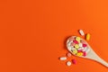 Mixed medicine pills, tablets on wooden spoon on orange background. M Royalty Free Stock Photo