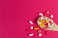 Mixed medicine pills, tablets on wooden spoon on pink background. Royalty Free Stock Photo