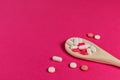 Mixed medicine pills, tablets on wooden spoon on pink background. Royalty Free Stock Photo