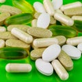 Mixed natural food supplement pills, omega 3, calcium, multivitamin and glucosamine capsules on green background. Royalty Free Stock Photo