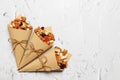 Mixed nuts and dried fruits in Retro Kraft Paper Cones on a light concrete background. Symbols of the Jewish holiday of Tu Bishvat