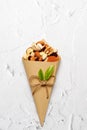 Mixed nuts and dried fruits in Retro Kraft Paper Cones on a light concrete background. Jewish holiday of Tu Bishvat
