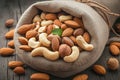 Mixed nuts scattered on gray wooden table from linen bag Royalty Free Stock Photo