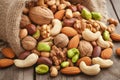 Mixed nuts scattered on gray wooden table from linen bag