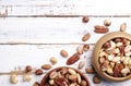 Trail mix with different kinds of nuts in brown wood bowl on scratched white wooden table background, soft daylight. Copy space. Royalty Free Stock Photo