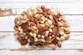 Trail mix with different kinds of nuts in brown wood bowl on scratched white wooden table background, soft daylight. Copy space. Royalty Free Stock Photo