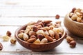 Trail mix with different kinds of nuts in brown wood bowl on scratched white wooden table background, soft daylight. Copy space. Royalty Free Stock Photo