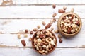 Trail mix with different kinds of nuts in brown wood bowl on scratched white wooden table background, soft daylight. Copy space. Royalty Free Stock Photo