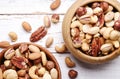 Trail mix with different kinds of nuts in brown wood bowl on scratched white wooden table background, soft daylight. Copy space. Royalty Free Stock Photo