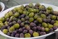 Mixed olives sprinkled with herbs in a white bowl