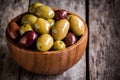 Mixed olives in a wooden bowl closeup on a rustic table