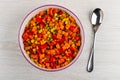 Mixed pepper, carrot, green peas, corn in ceramic bowl, spoon on table. Top view Royalty Free Stock Photo