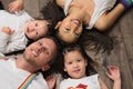 Mixed race Asian American family laying on floor looking at camera