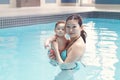 Mixed race asian mother training teaching her newborn baby to float in swimming pool Royalty Free Stock Photo