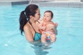 Asian mother training teaching her newborn baby to float in swimming pool. Royalty Free Stock Photo