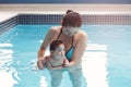 Mixed race asian mother training teaching her newborn baby to float in swimming pool Royalty Free Stock Photo