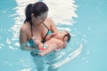 Mixed race asian mother training teaching her newborn baby to float in swimming pool Royalty Free Stock Photo