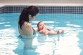 Mixed race asian mother training teaching her newborn baby to float in swimming pool Royalty Free Stock Photo