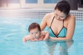 Mixed race asian mother training teaching her newborn baby to float in swimming pool Royalty Free Stock Photo