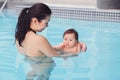Mixed race asian mother training teaching her newborn baby to float in swimming pool Royalty Free Stock Photo