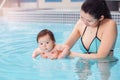 Mixed race asian mother training teaching her newborn baby to float in swimming pool Royalty Free Stock Photo