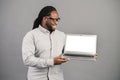 Smiling African-American man with laptop isolated on grey Royalty Free Stock Photo