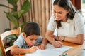 Mixed race boy learning and studying in homeschool with mom. Woman helping son with homework and assignments at home Royalty Free Stock Photo