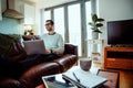 Mixed race business man sitting on couch concentrating typing on laptop working from home Royalty Free Stock Photo