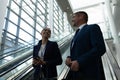 Mixed-race of businessman and businesswoman interacting with each other near escalator Royalty Free Stock Photo