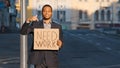 Mixed Race businessman holding sign Need Work points index finger. Portrait of Young man standing outdoor hold poster