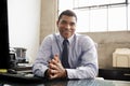 Mixed race businessman at an office desk smiling to camera Royalty Free Stock Photo