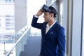 Mixed-race businessman using virtual reality headset standing in modern office Royalty Free Stock Photo