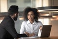 Mixed race businesswoman and colleague discussing project, using laptop Royalty Free Stock Photo