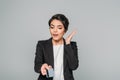 Mixed race businesswoman gesturing while holding credit card isolated on grey