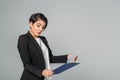 Mixed race businesswoman looking at clipboard and gesturing on grey