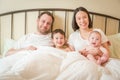 Mixed Race Chinese and Caucasian Baby Boys Laying In Bed with Their Father and Mother