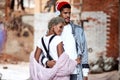 Mixed race confident stylish male wears headphones, embraces his mulatto girlfriend, pose together against brick wall