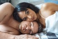 Mixed Race Couple. Young man and woman at home lying on bed head to head smiling relaxed close-up