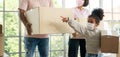 Mixed Race families are carrying cardboard boxes and walking from the front door into the house in a new house on moving day. Royalty Free Stock Photo