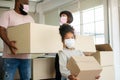 Mixed Race families are carrying cardboard boxes and walking from the front door into the house in a new house on moving day. Royalty Free Stock Photo