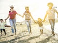 Mixed race family friends running and having fun on the beach - Diverse culture parents and children enjoying time together - New Royalty Free Stock Photo