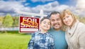 Mixed Race Family In Front of House and Sold For Sale Real Estate Sign Royalty Free Stock Photo