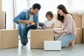 Mixed race family, Latino father and Asian mother, with little cute daughter using scotch tape for packing cardboard boxes