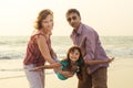 Mixed race family playing with child on sea at sunset Royalty Free Stock Photo