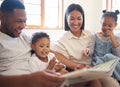 Mixed race family reading a book together on the couch at home. Hispanic mother and father teaching their little son and Royalty Free Stock Photo