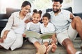 Mixed race family reading a book together on the floor at home. Hispanic mother and father teaching their little son and Royalty Free Stock Photo